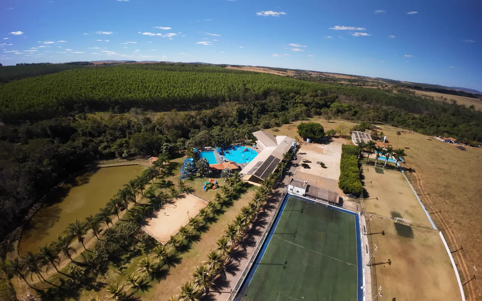 Vista aérea do clube com lago, quadra de areia e campo de futebol